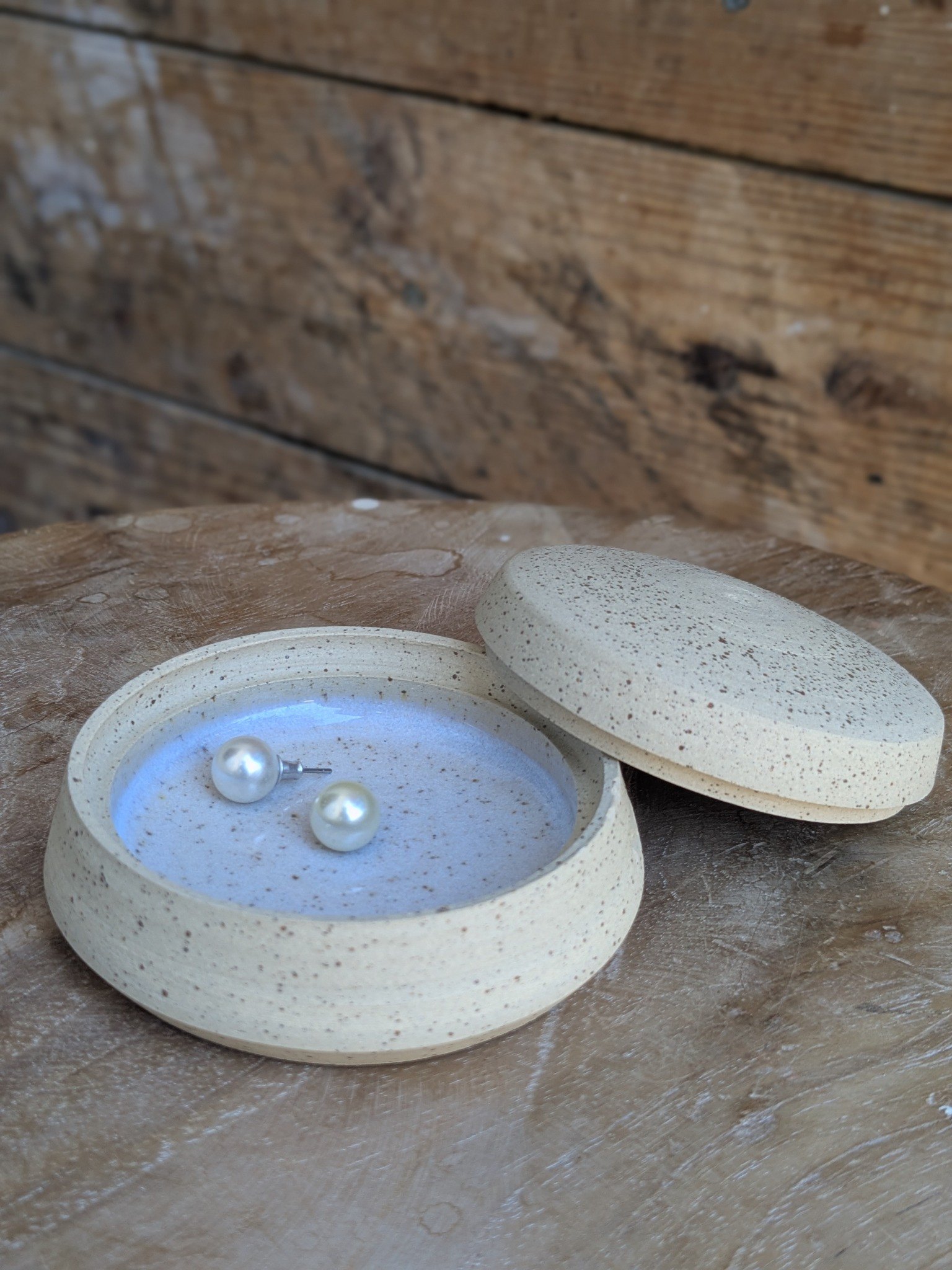 Boîte en céramique mouchetée, ouverte avec une paire de boucles d’oreilles en perles